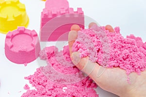 Hands of a kid playing with pink magic sand