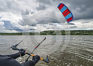 Hands of kitesurfer hold kitesurfing bar with run kite in air