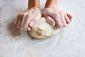 Hands knead dough