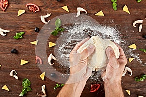 Hands knead the dough for pizza making