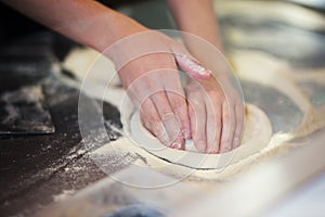 Hands knead the dough for pizza making