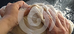 Hands knead the dough. The woman kneaded dough for baking or dumplings. Preparation of flour, water and egg mass