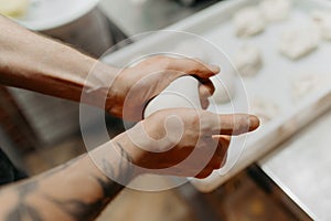 hands kneading bread dough on a cutting board. knead the pizza dough. ball of dough in male hands