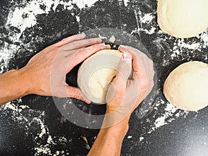 Hands kneading dough on black board