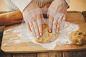 Hands kneading gingerbread dough on wooden board with rolling pin and flour. Making christmas gingerbread cookies. Woman preparing