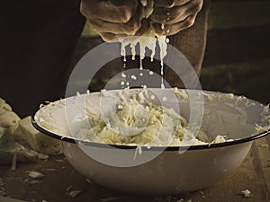 Hands kneading sauerkraut - salty cabbage juice is dripping down photo