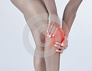 Hands, knee pain and injury for woman in studio with red glow, overlay and ligament strain by with background. Girl