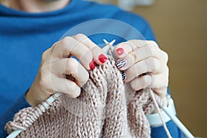 Hands of knitting woman in blue dress, close up photo