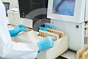 Hands of laboratory assistant loading sample tubes for coagulation test analysis