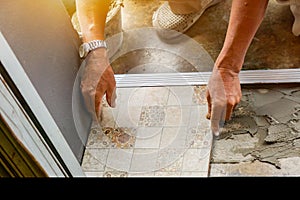 Hands of laborer working install tiled floor at construction site