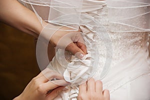 Hands lacing brides dress