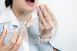 Hands of lady girl with occlusal splint to protect teeth from grinding caused by bruxism,woman patient holding bite plate silicone