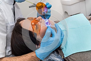 Hands with lamp and patient in protective glasses