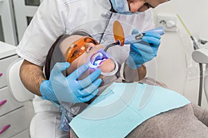 Hands with lamp and patient in protective glasses