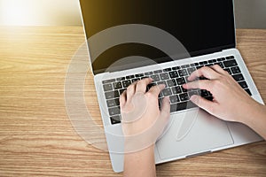 Hands on the laptop on the brown wood table in the room