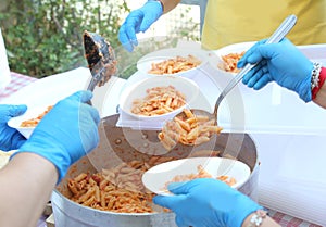 hands with latex gloves during meal distribution of pasta with t