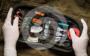 Hands in latex gloves opening a first aid kit. First aid in an emergency