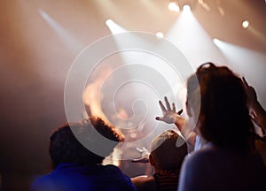 Hands, lighting and excited fans at music festival, crowd watching live band performance with musician on stage