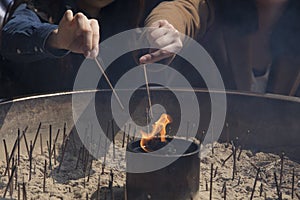 Hands lighting incense sticks at the temple of Todai-ji in nara in japan