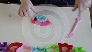 Hands of little girl 3-5 years old playing pink play dough with plastic molds