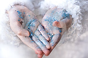 Hands of a little girl in blue sequins