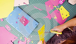 Hands of little girl cutting colored paper with scissors