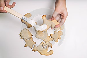 Hands of little girl making traditional Christmas cookies. The child decorates homemade Christmas cookies on a white table