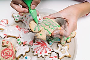 Hands of little girl making traditional Christmas cookies. The child decorates homemade Christmas cookies on a white table