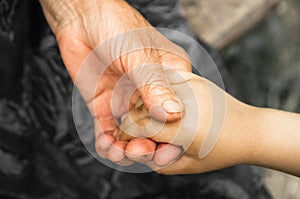 Hands of a little girl and an old grandmother. Hands of a little kids holding elderly man, World Kindness Day concept