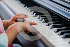 Hands of little girl playing piano, selective focus