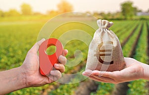 Hands with location pin and euro money bag. Land market. Buying and selling land. Estimation cost of plots. Legal regulation