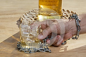 Hands lock chain a glass of whiskey to stop drinking. Alcoholism concept