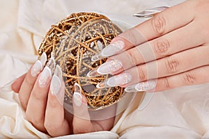 Hands with long artificial french manicured nails and Christmas ball