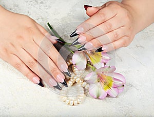 Hands with long artificial french manicured nails and lily flowers