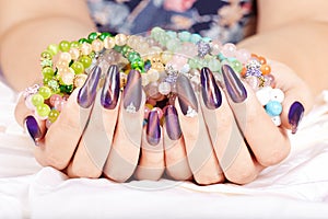 Hands with long artificial manicured nails holding colorful bracelets