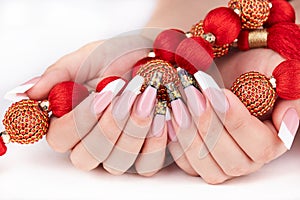 Hands with long artificial white and black french manicured nails and red necklace