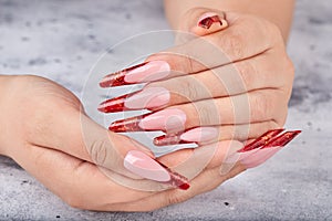 Hands with long red artificial french manicured nails photo