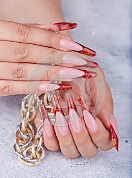 Hands with long red artificial french manicured nails holding a chain necklace