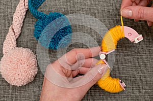 Hands Looping Yellow Yarn Around Pom-Pom Maker