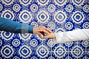 Hands of a loving couple hold together in a Talavera background in Latin america mexico city