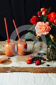 Hands makes strawberry smoothies in wooden table . Fresh strawbe