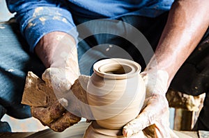 Hands of making clay pot on the pottery wheel ,select focus, close-up.