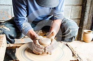 Hands of making clay pot on the pottery wheel ,select focus, close-up.