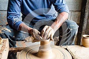 Hands of making clay pot on the pottery wheel ,select focus, close-up.