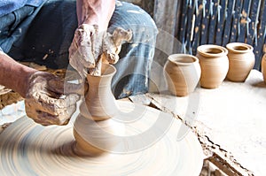 Hands of making clay pot on the pottery wheel ,select focus, close-up.