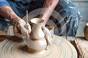 Hands of making clay pot on the pottery wheel ,select focus, close-up.