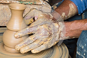 Hands of making clay pot on the pottery wheel ,select focus, close-up.