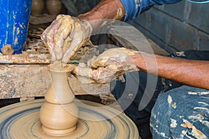 Hands of making clay pot on the pottery wheel ,select focus, close-up.