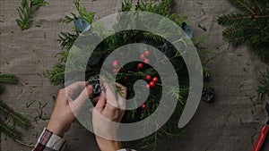 Hands making evergreen Christmas flower arrangement. DIY Xmas home decoration.