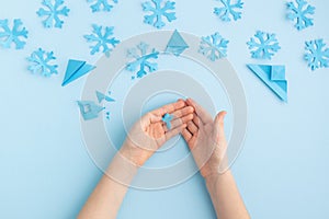 Hands making paper snowflakes on blue child hands